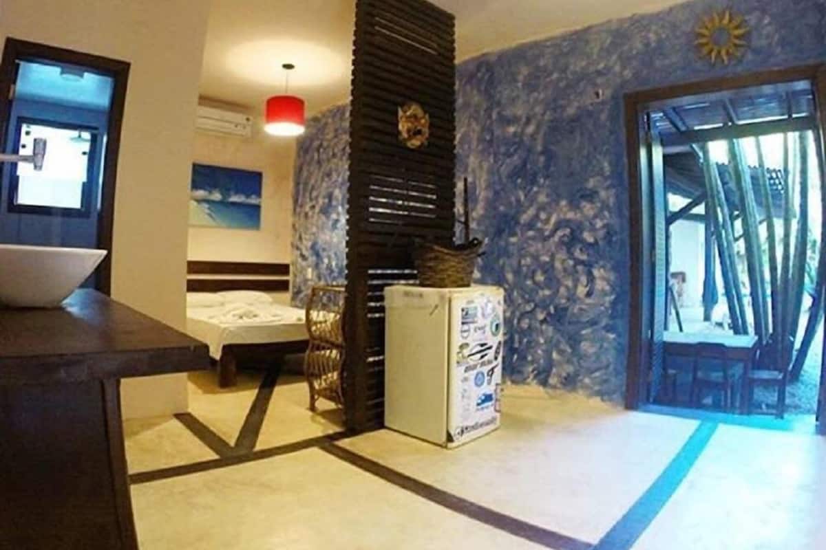 Une chambre d’hôtel équipée d’un lit, d’un bureau, d’un réfrigérateur et d’un mur agrémenté d’un élément décoratif.