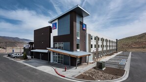 A modern building with a flat roof, large windows, and a parking lot with marked handicapped spaces. - Studio 6 Mccarran, NV - Sparks - Tahoe - Reno Industrial Center (Sparks)