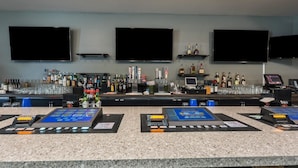 A bar area with multiple screens, a variety of liquor bottles, and a digital payment terminal. - Studio 6 Mccarran, NV - Sparks - Tahoe - Reno Industrial Center (Sparks)