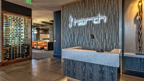A reception area with a wine rack, a reception desk, and a wall with the word 'harth' illuminated. - Hilton Franklin Cool Springs (Franklin)