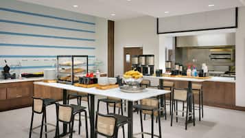 Een moderne hotelkeuken met een buffetopstelling, inclusief een etalage met gebak en een schaal bananen.