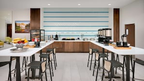 A modern hotel dining area with a long counter, multiple seating options, and a variety of breakfast items. - Hilton Garden Inn Boise Downtown (Boise)