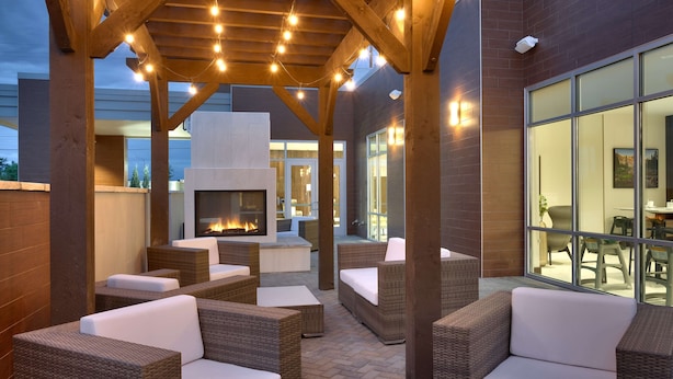 An outdoor patio area with wicker furniture and a built-in fireplace. - Hilton Garden Inn Boise Downtown (Boise)