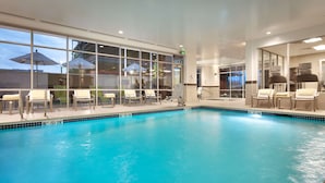 An indoor swimming pool with clear blue water, surrounded by lounge chairs and a pool lift. - Hilton Garden Inn Boise Downtown (Boise)
