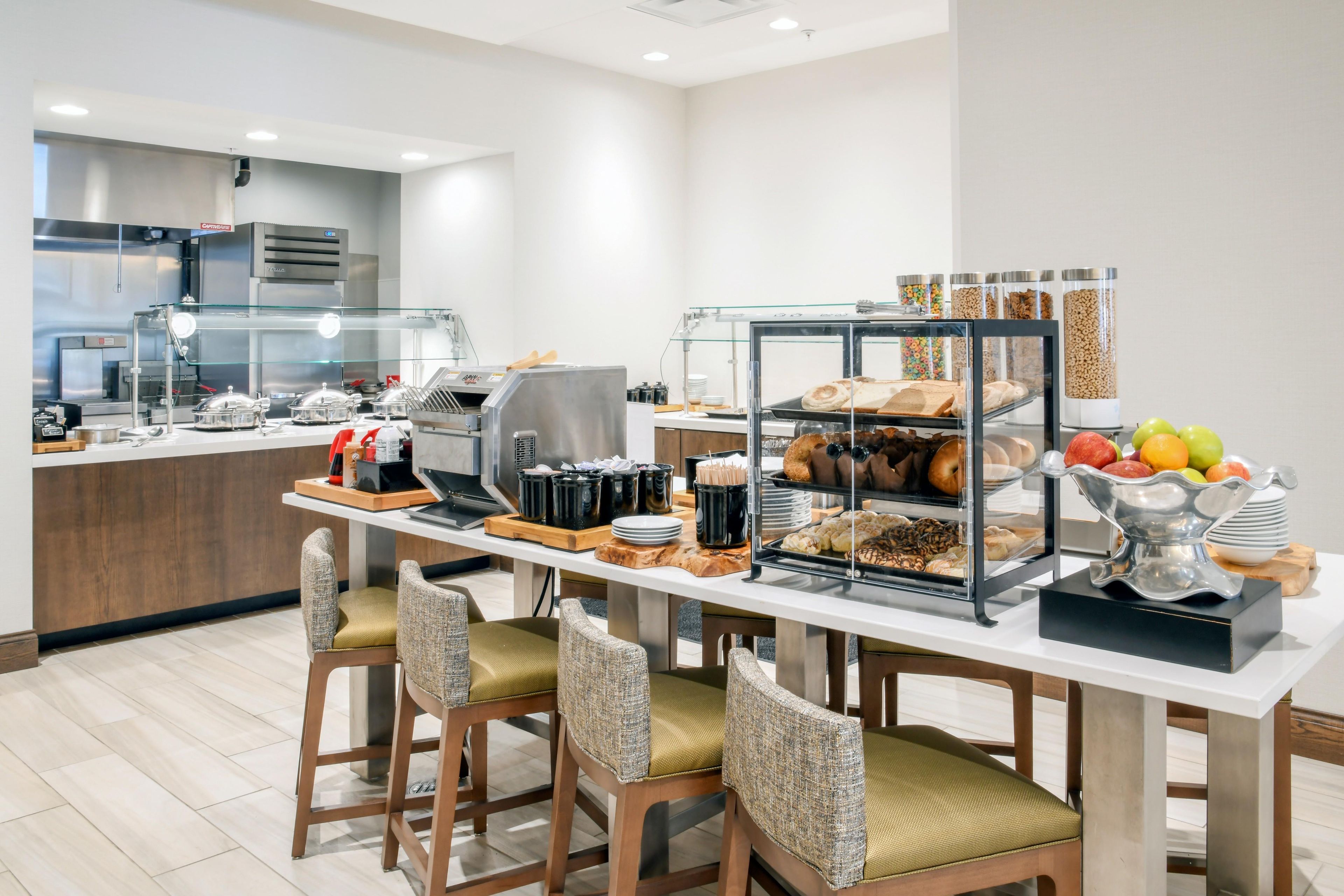 Un buffet de petit-déjeuner proposant une variété d’aliments, un coin café et des espaces pour s’asseoir.