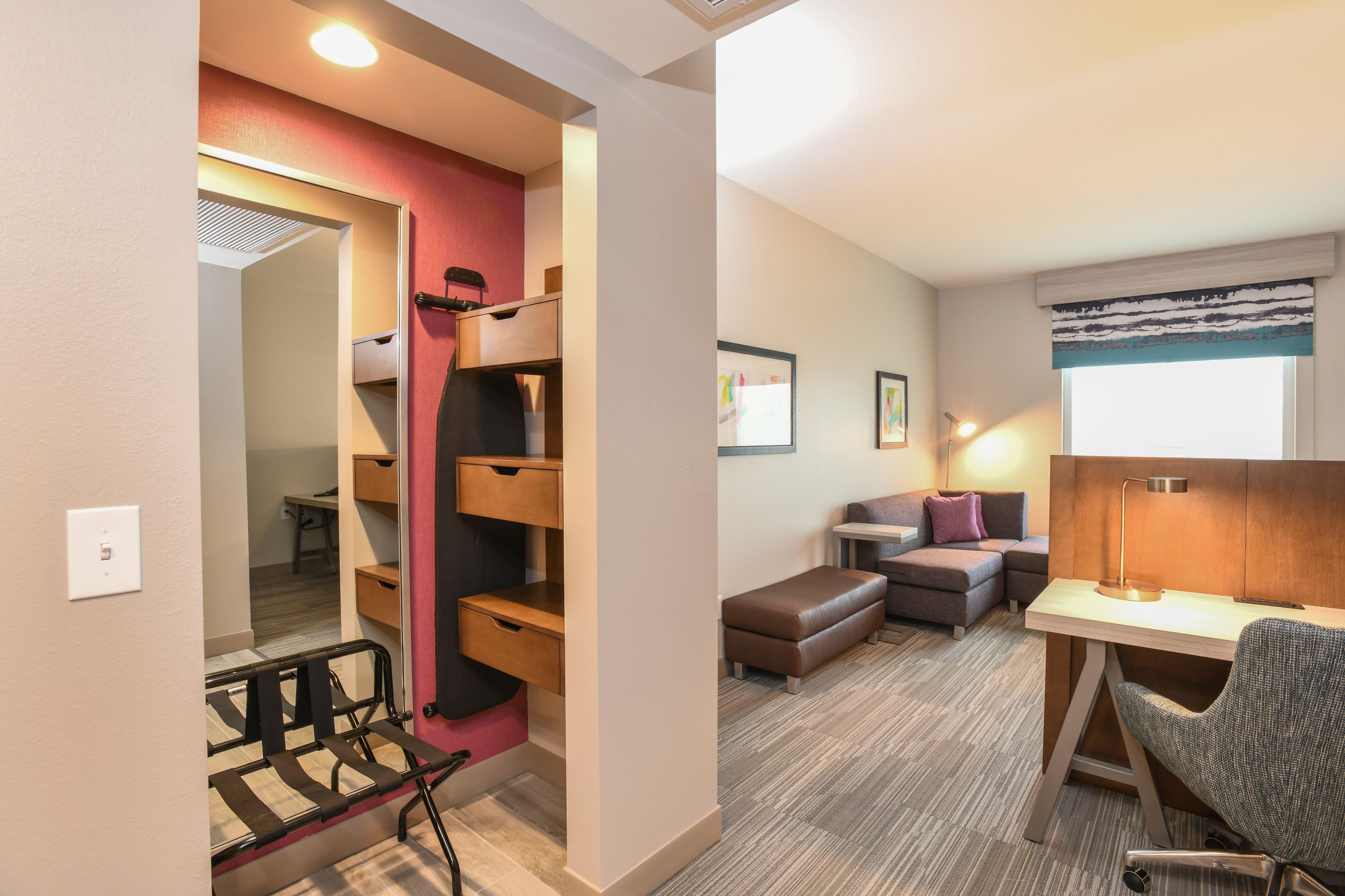Una habitación de hotel con cama, escritorio, silla, sofá y una pequeña kitchenette.