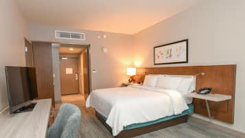 Une chambre d’hôtel équipée d’un lit, d’une table de chevet, d’une lampe, d’un téléphone et d’un téléviseur.