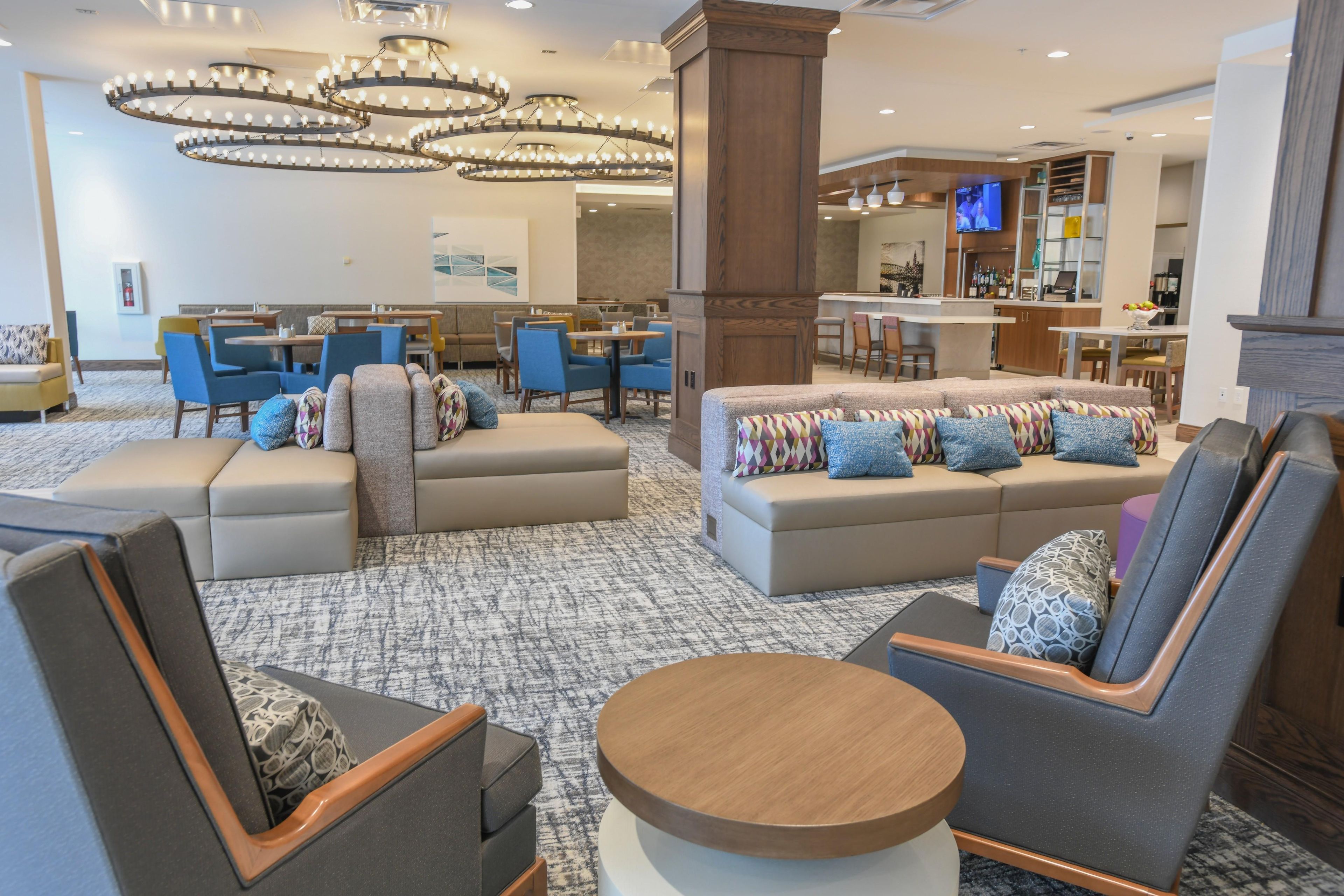 A hotel lobby with seating areas, a bar, and a television screen.