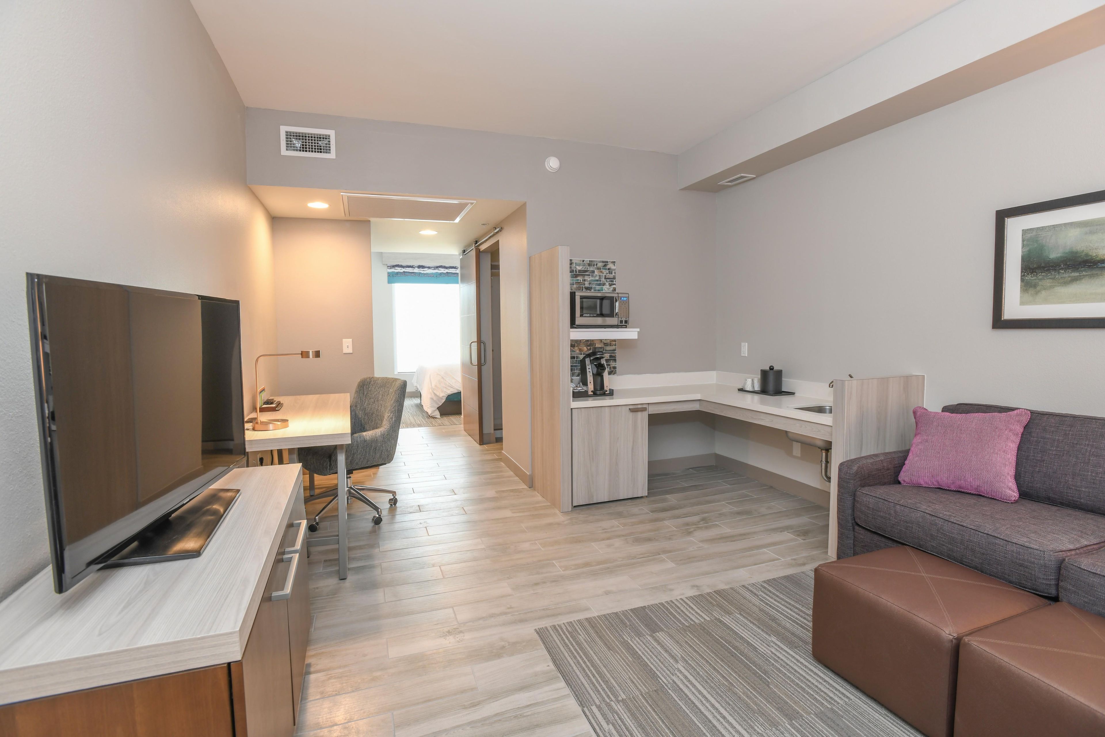 Un apartamento moderno con kitchenette, comedor, sala de estar con sofá y televisor.