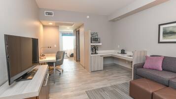 Un apartamento moderno con kitchenette, comedor, sala de estar con sofá y televisor.