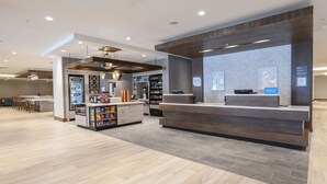 Um hall moderno de hotel com balcão de recepção, minibar e área de estar.