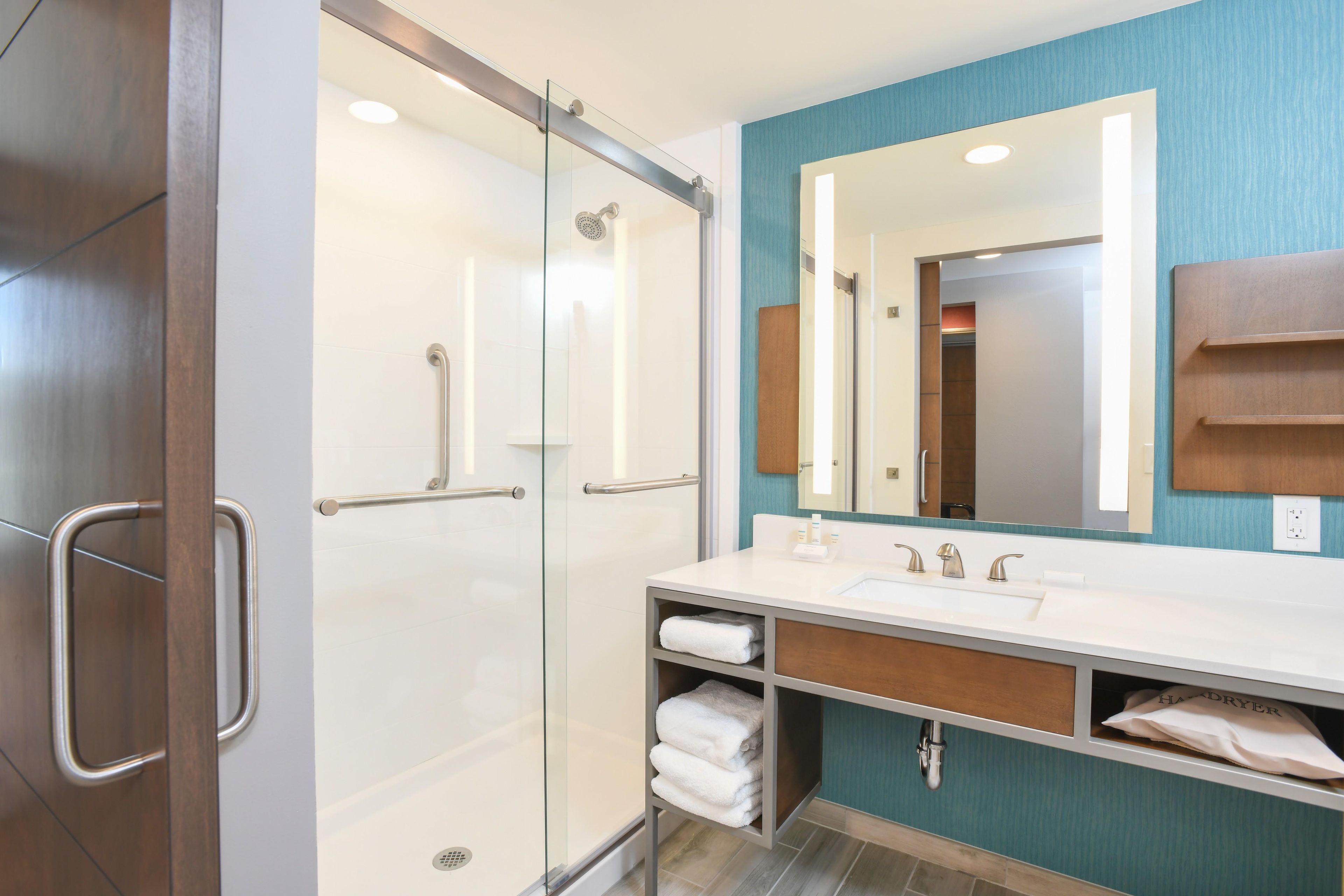 A modern bathroom with a glass shower enclosure, a vanity with a sink, and a mirror.