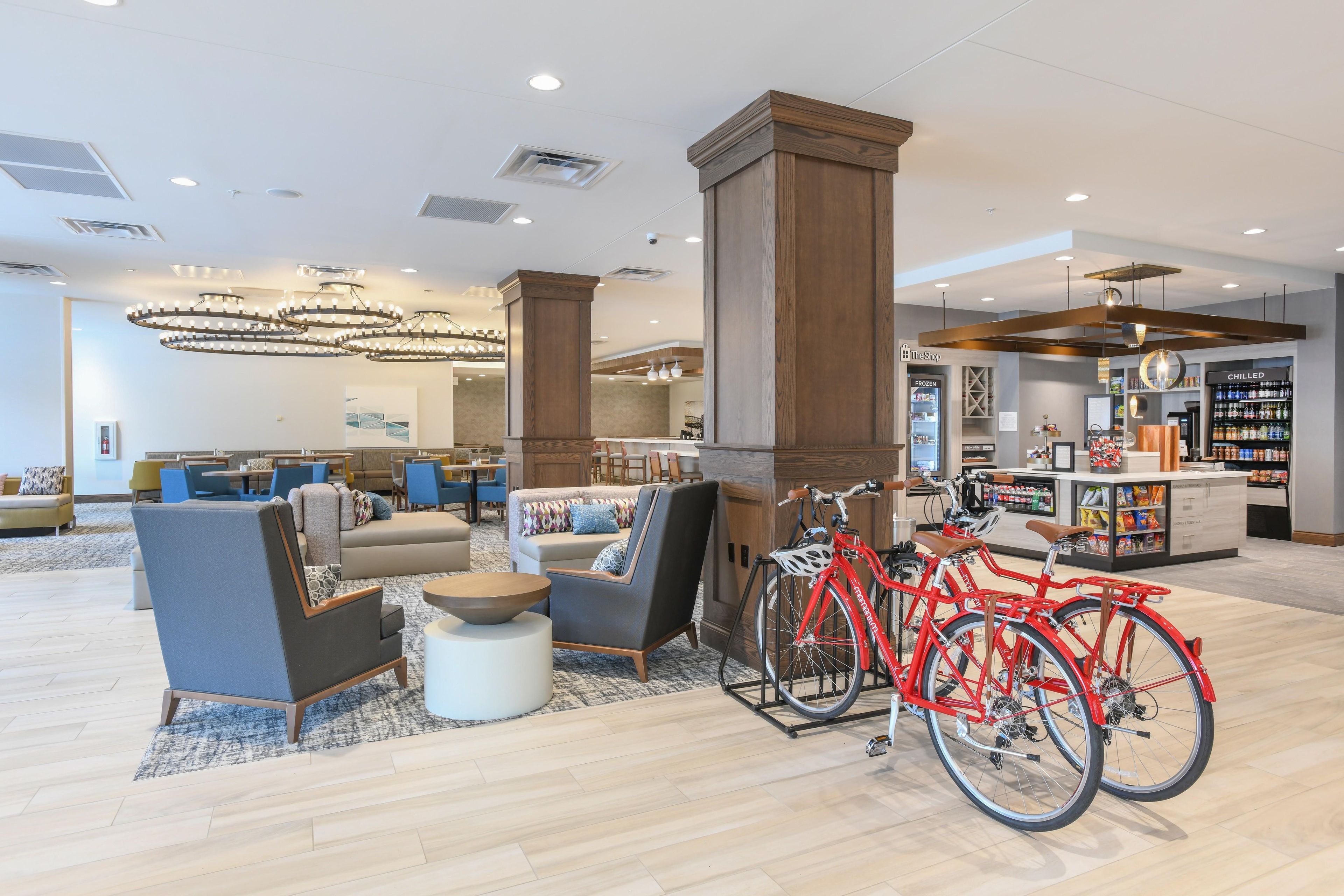 A spacious lobby with seating areas, a bike rental station, and a refrigerated beverage display.