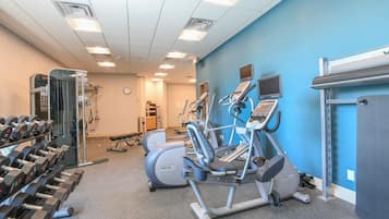 Une salle de sport équipée de tapis de course, de vélos elliptiques et de poids libres.