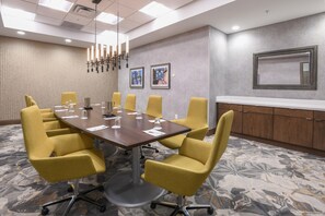 A conference room with a large table, yellow chairs, a white counter, and framed pictures on the wall. - Hilton Garden Inn Cincinnati Midtown (Cincinnati)