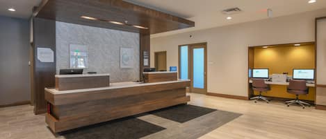 A reception desk with a wooden finish, a digital display, and a carpeted floor.