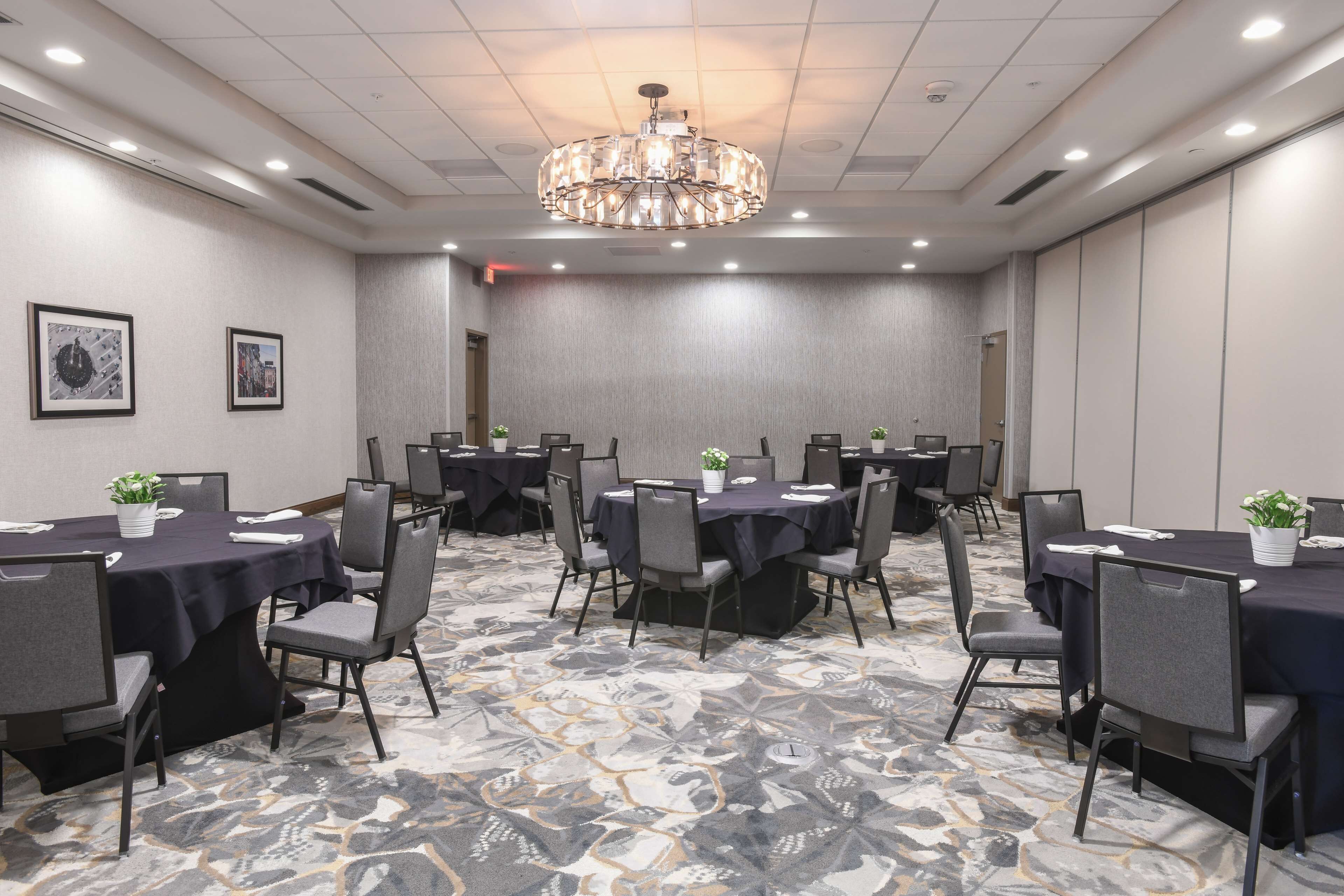 Un salón de conferencias con mesas redondas, sillas y una araña.
