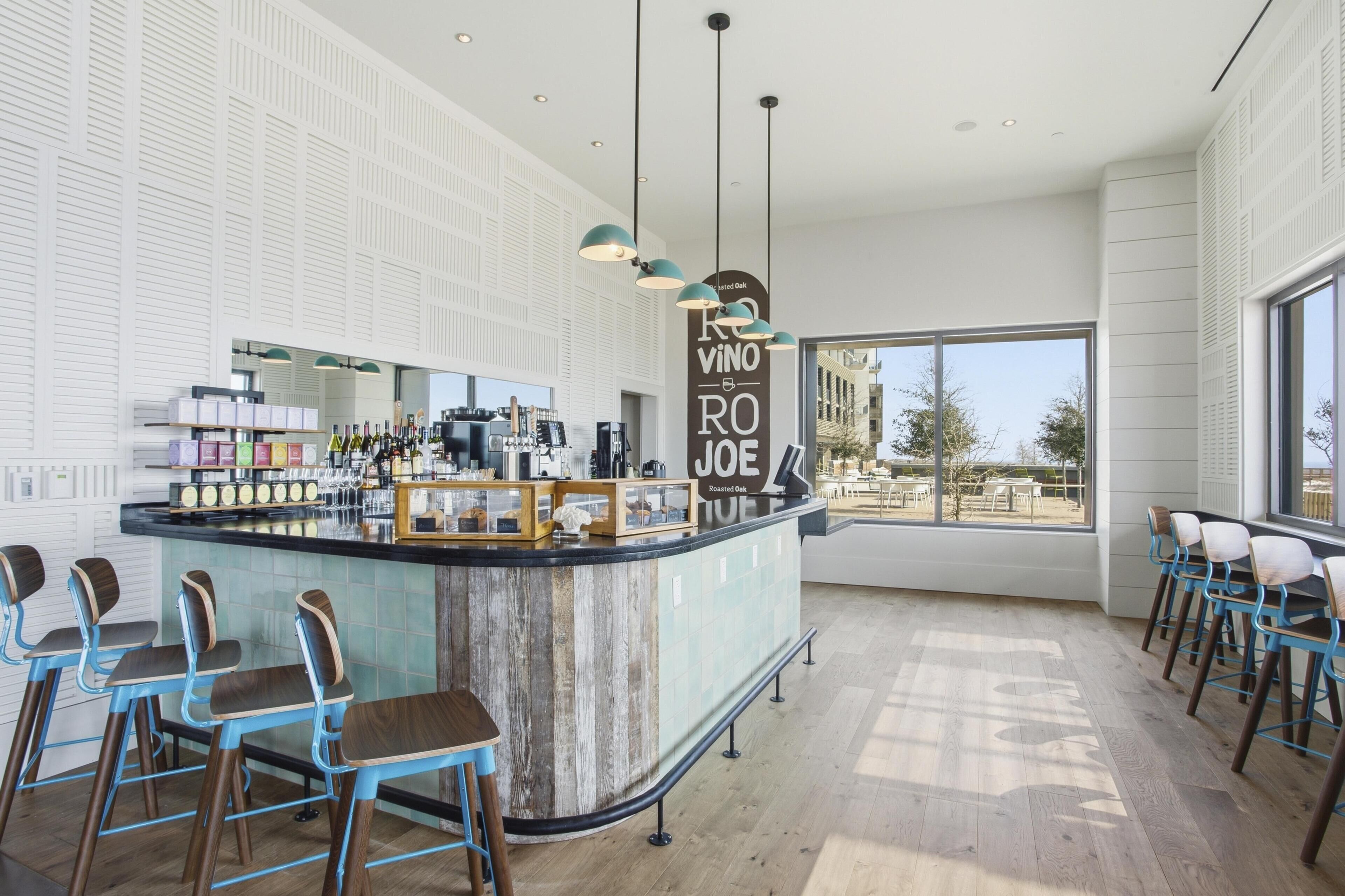Eine moderne Bar mit einer zentralen Theke, Barhocker und einem großen Fenster mit Blick.