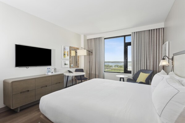 A modern hotel room with a large bed, a flat-screen TV, a desk, and a chair.