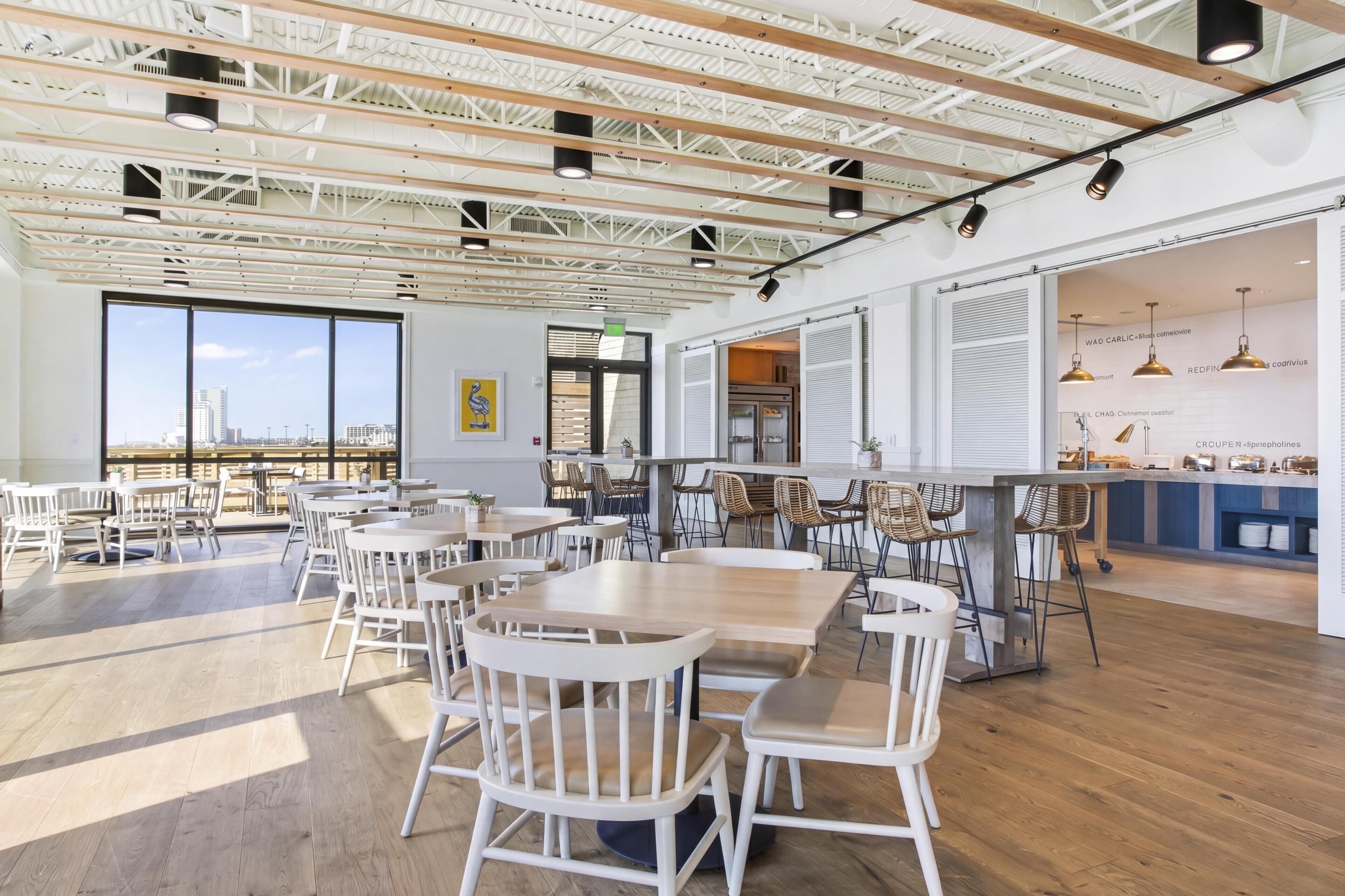 A spacious dining area with high ceilings, large windows, and a view of the cityscape.