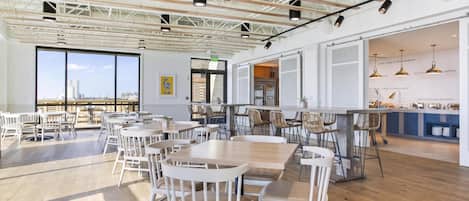 Une salle à manger spacieuse avec de hauts plafonds, de grandes fenêtres et une vue sur le paysage urbain.