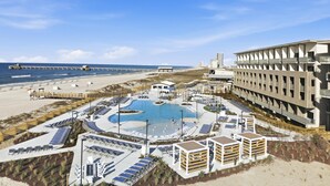 Un complexe hôtelier doté d’une piscine centrale, de chaises longues et d’un espace plage.