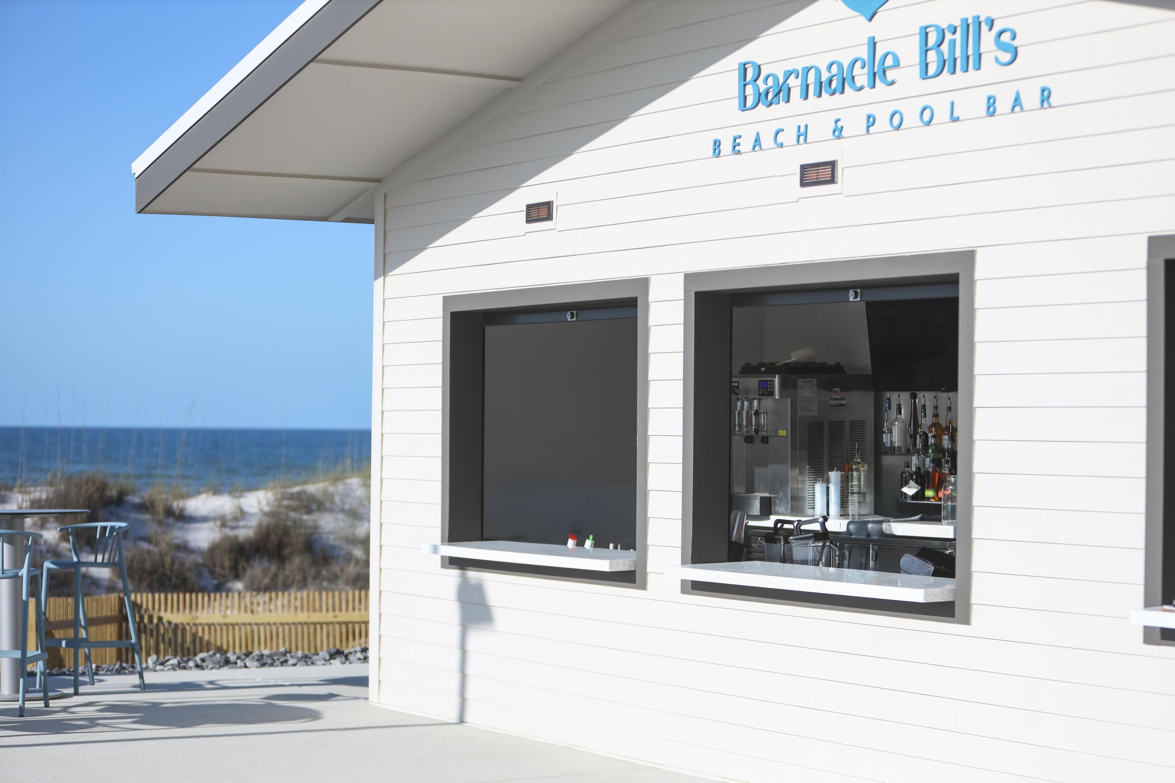 A beach bar with a clear view of the ocean, a bar counter, and outdoor seating.