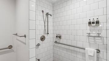 Ein modernes Badezimmer mit weißen Fliesen, einer Dusche, einer Haltestange und einem Handtuchhalter.