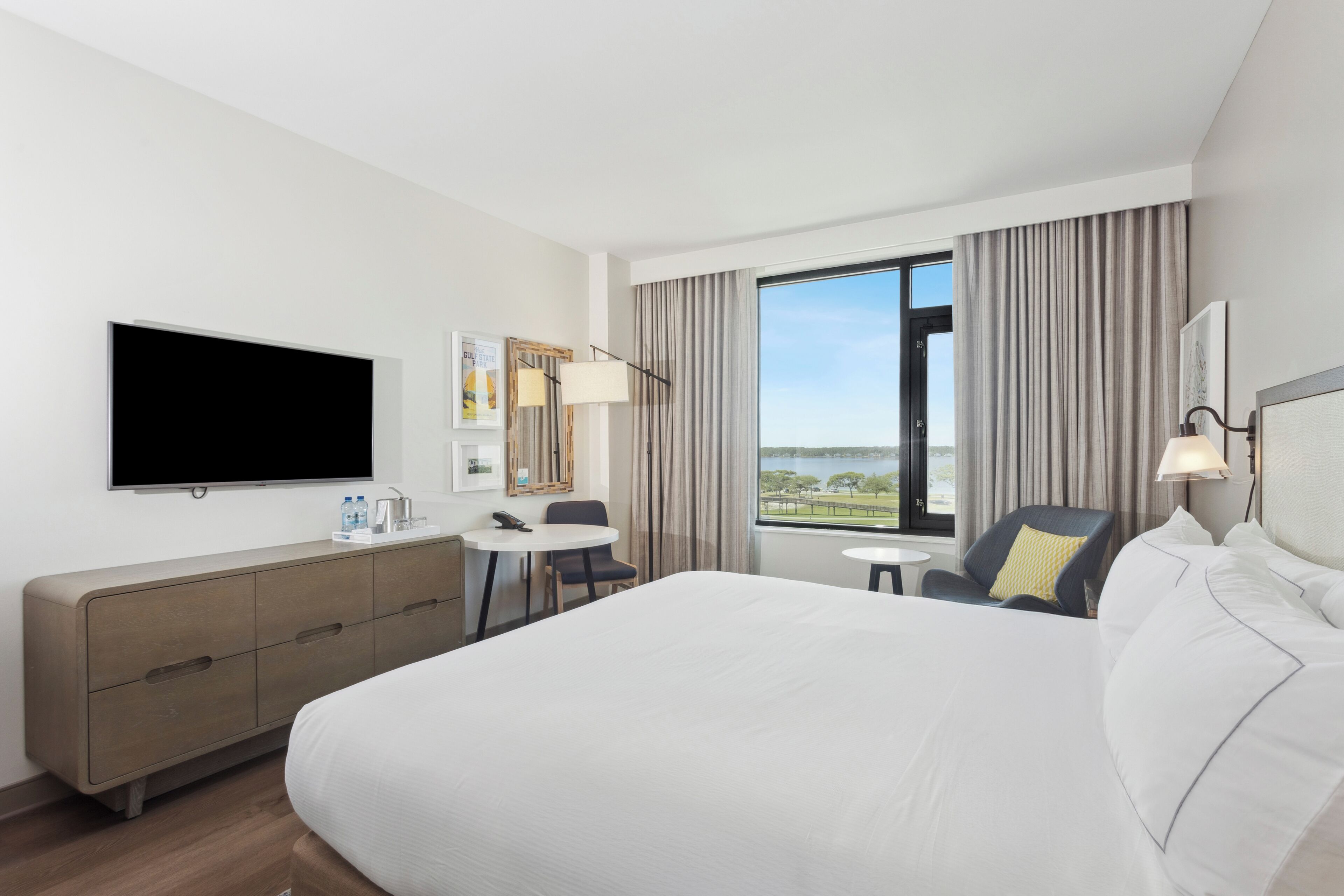 A hotel room with a large bed, a flat-screen TV, a desk, and a chair.