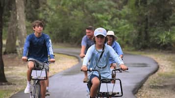 Un grupo de personas andando en bicicleta por un camino pavimentado bordeado de árboles.
