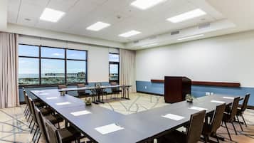 A conference room with a long table, chairs, a podium, and large windows with a view.