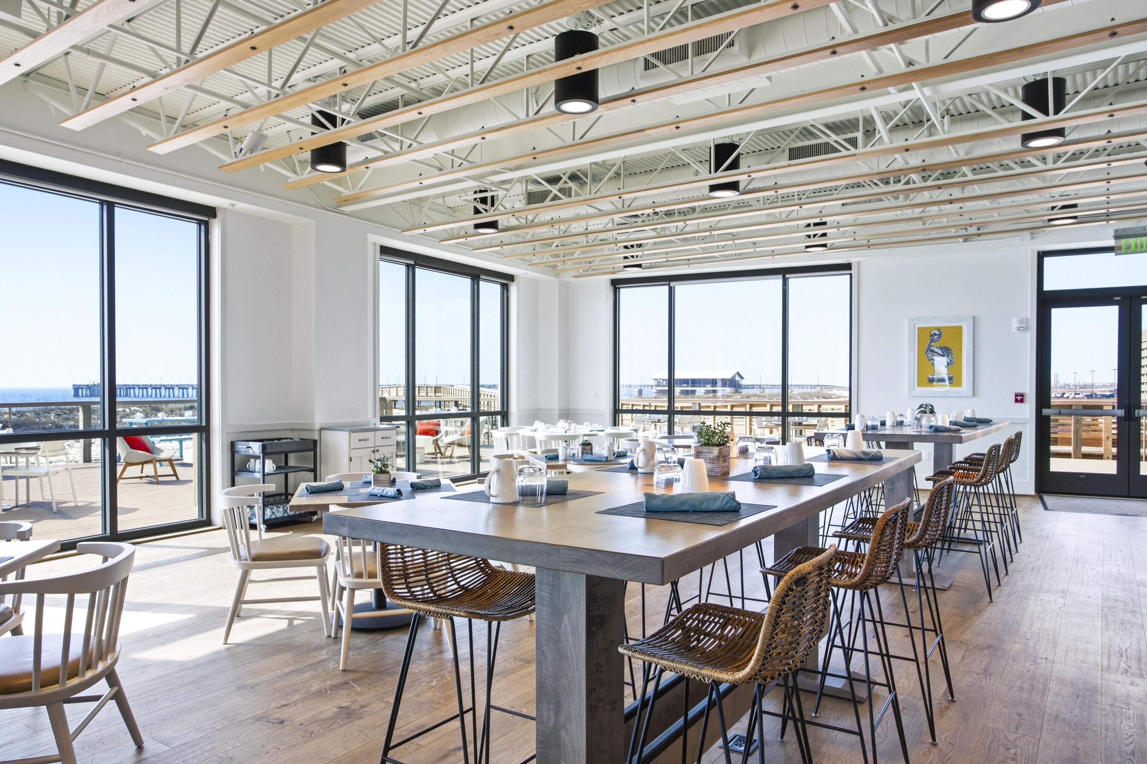 Un comedor moderno con una mesa larga, sillas y ventanas amplias que ofrecen vistas de la ciudad.