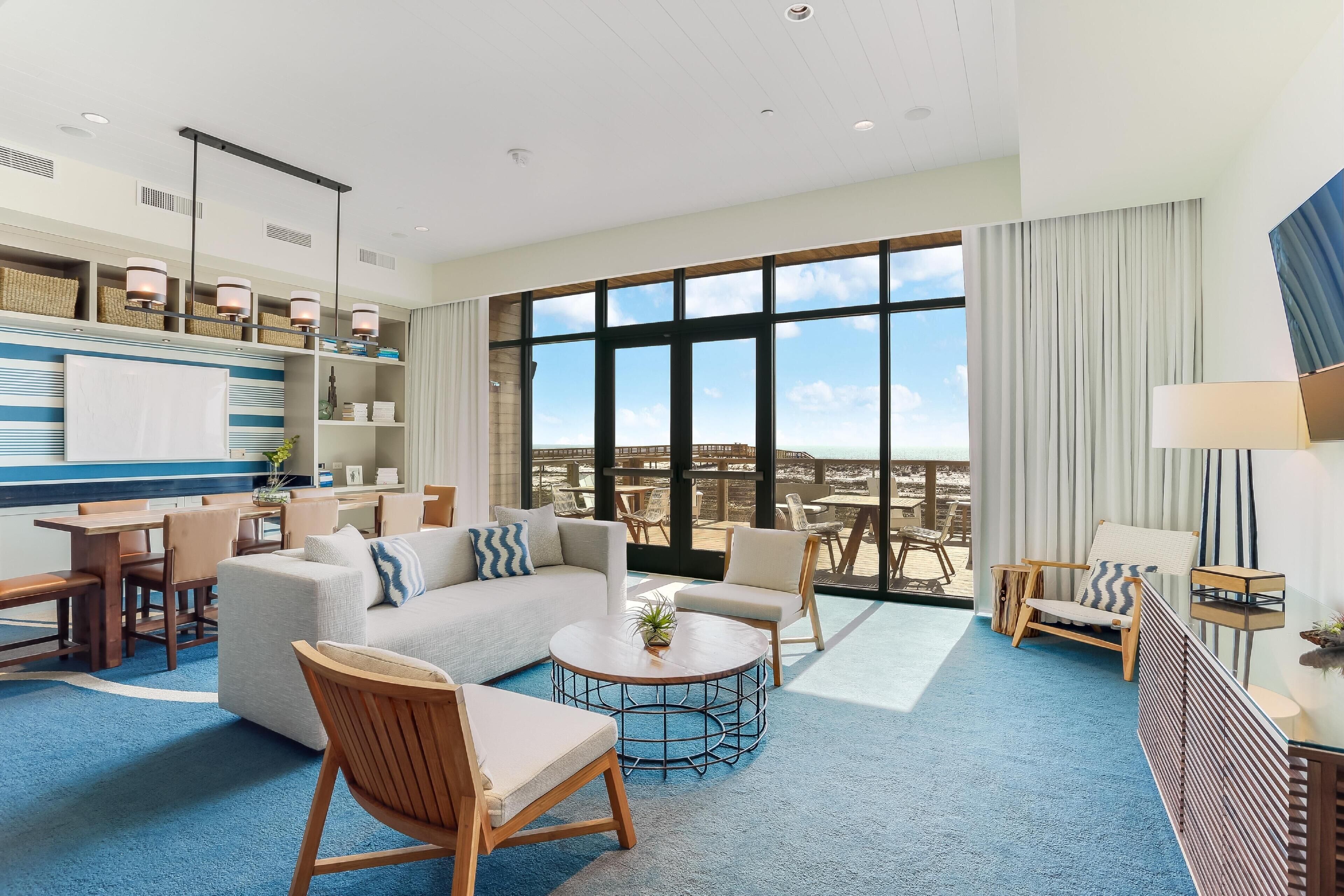 A spacious living area with a large window, a sofa, chairs, a coffee table, and a dining area.