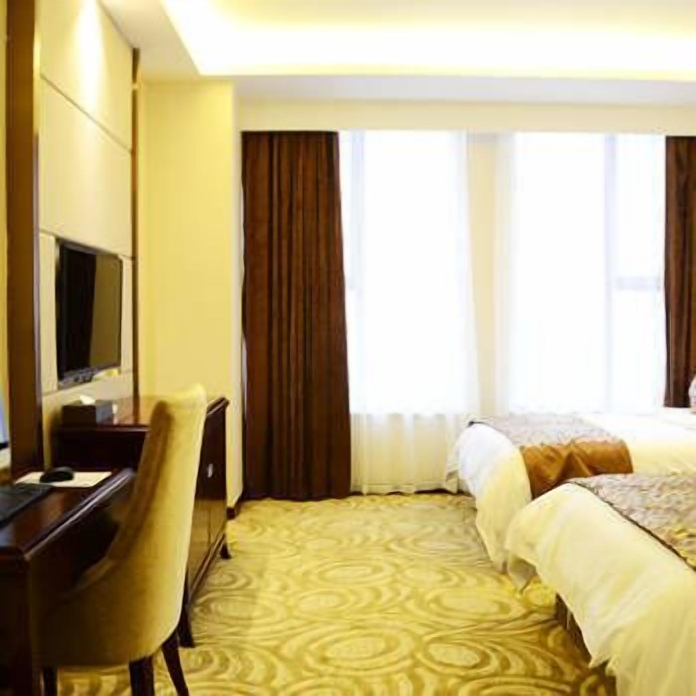 A hotel room with a bed, a desk, a chair, and a television.