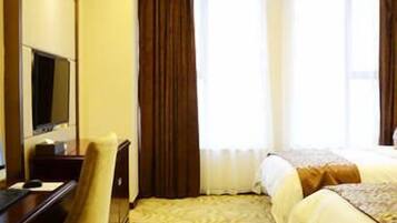 A hotel room with a bed, a desk, a chair, and a television.