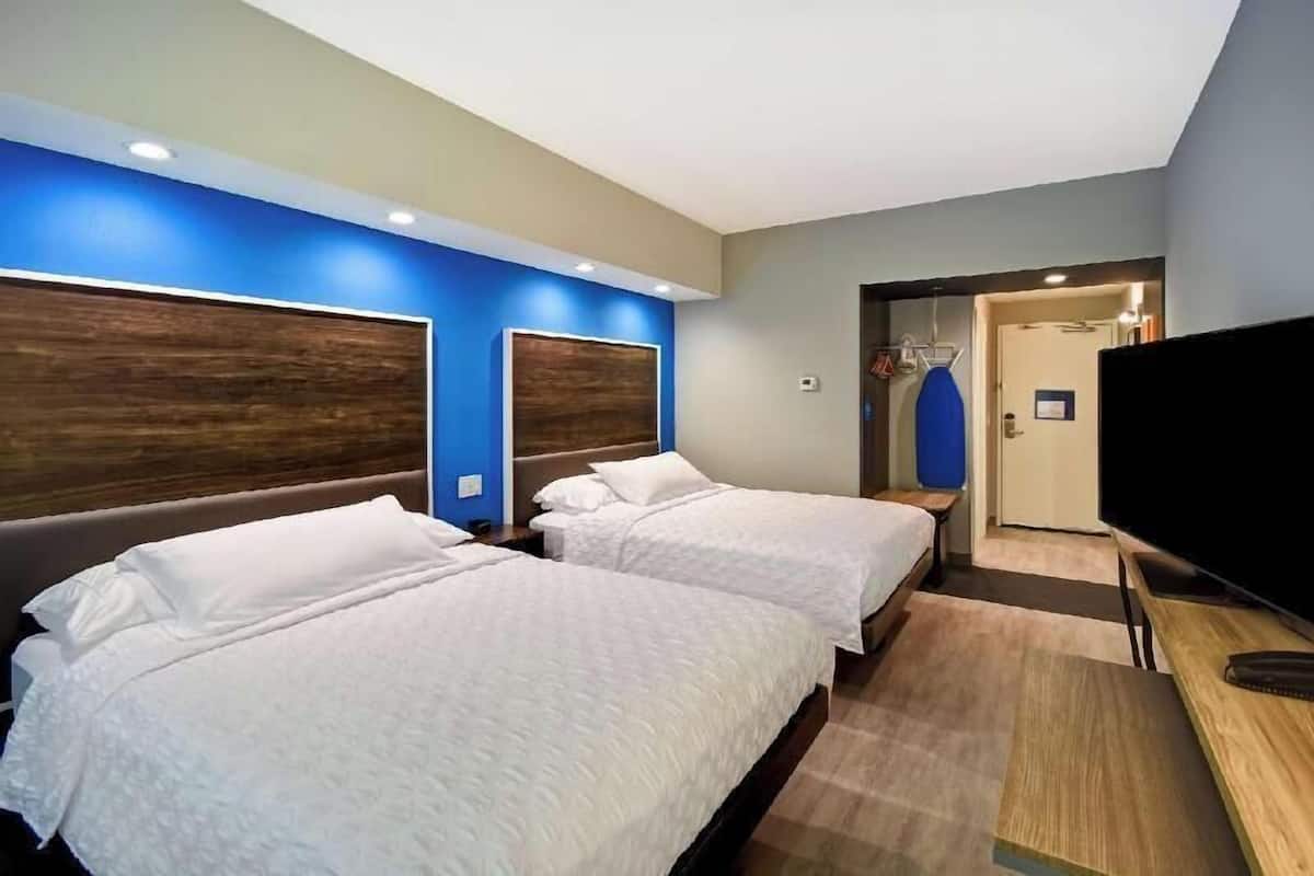 Een hotelkamer met twee bedden, een televisie en een douche.