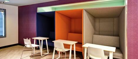 Un espacio de oficina moderno con tres mesas y sillas blancas, una pared morada y un papel tapiz estampado.