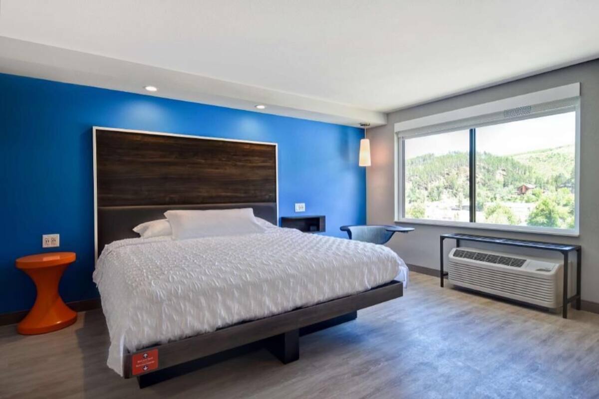 Een moderne hotelkamer met een groot bed, uitzicht op groen en een raam met een vrij uitzicht.