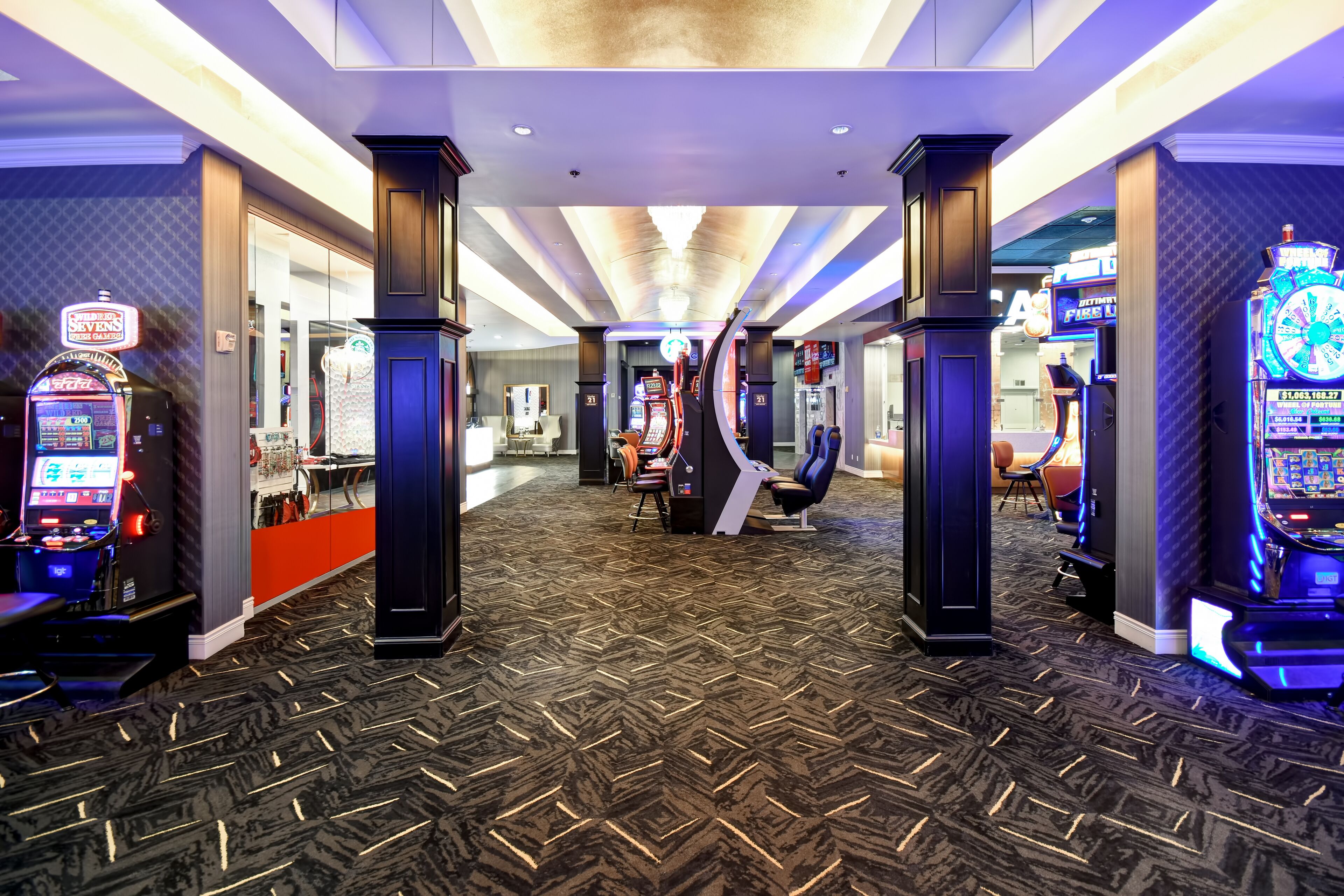 Een hotel lobby met een patroon vloerkleed, speelautomaten en een zithoek.