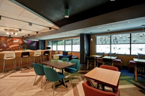 Ein modernes Restaurant mit Holztischen und -stühlen, großen Fenstern und einem Wandbild.