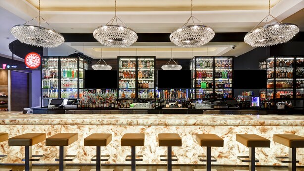 Un espace bar doté de comptoirs en marbre, de tabourets de bar et de lustres en cristal.
