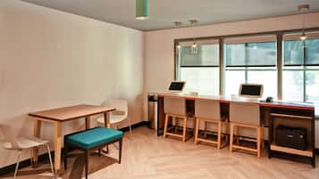Un espacio de oficina moderno con un escritorio de madera, dos sillas, un banco y un equipo informático.
