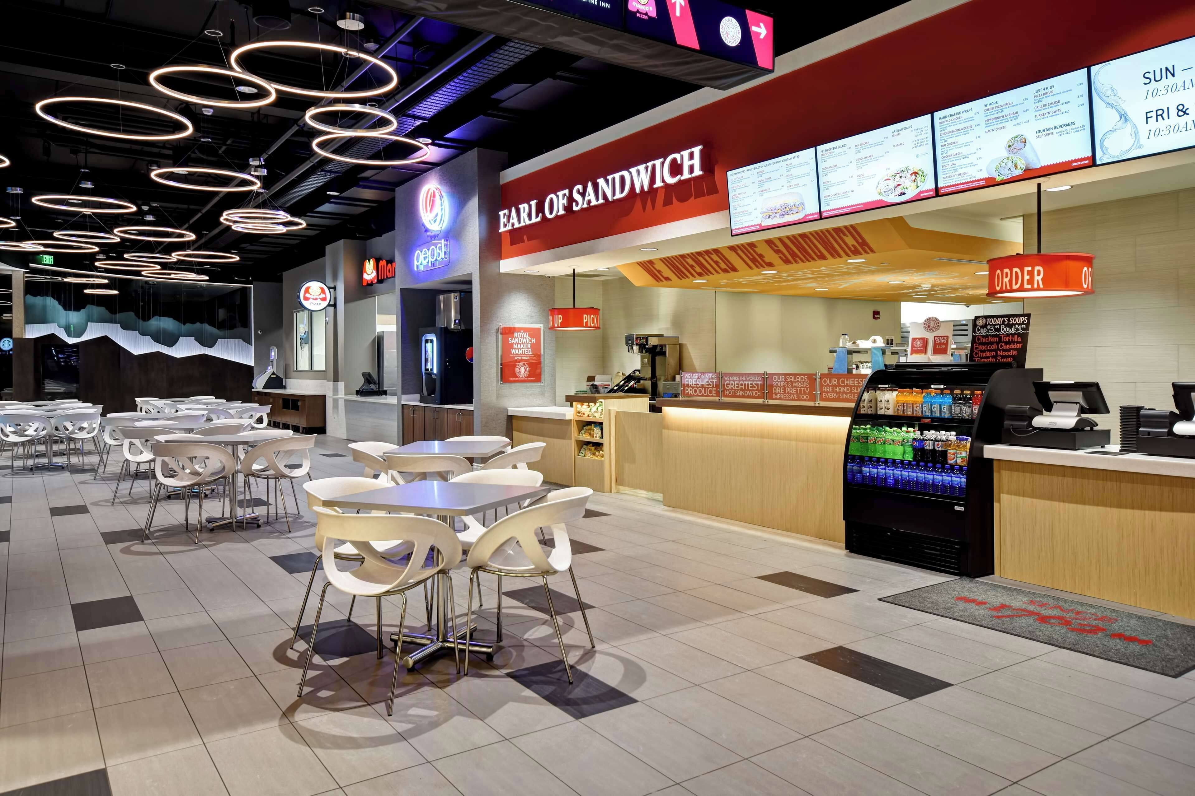 A fast-food restaurant with a menu board, a Pepsi sign, and a vending machine.