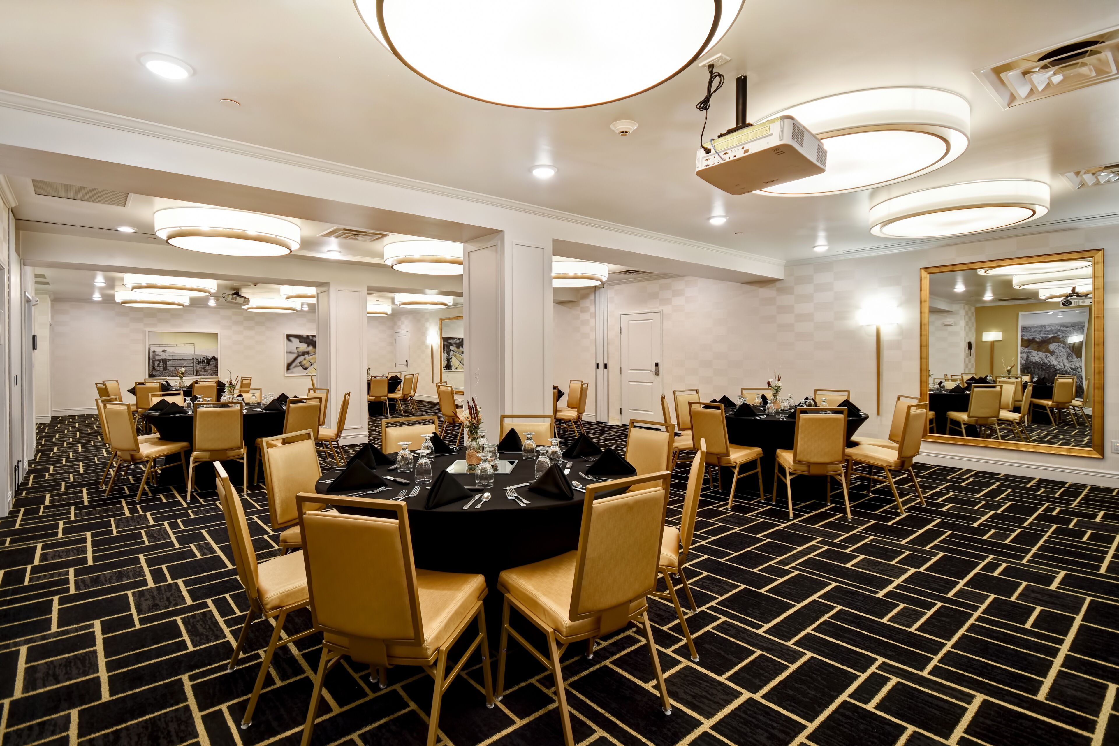 Een vergaderzaal met ronde tafels, stoelen en een vloerbedekking.