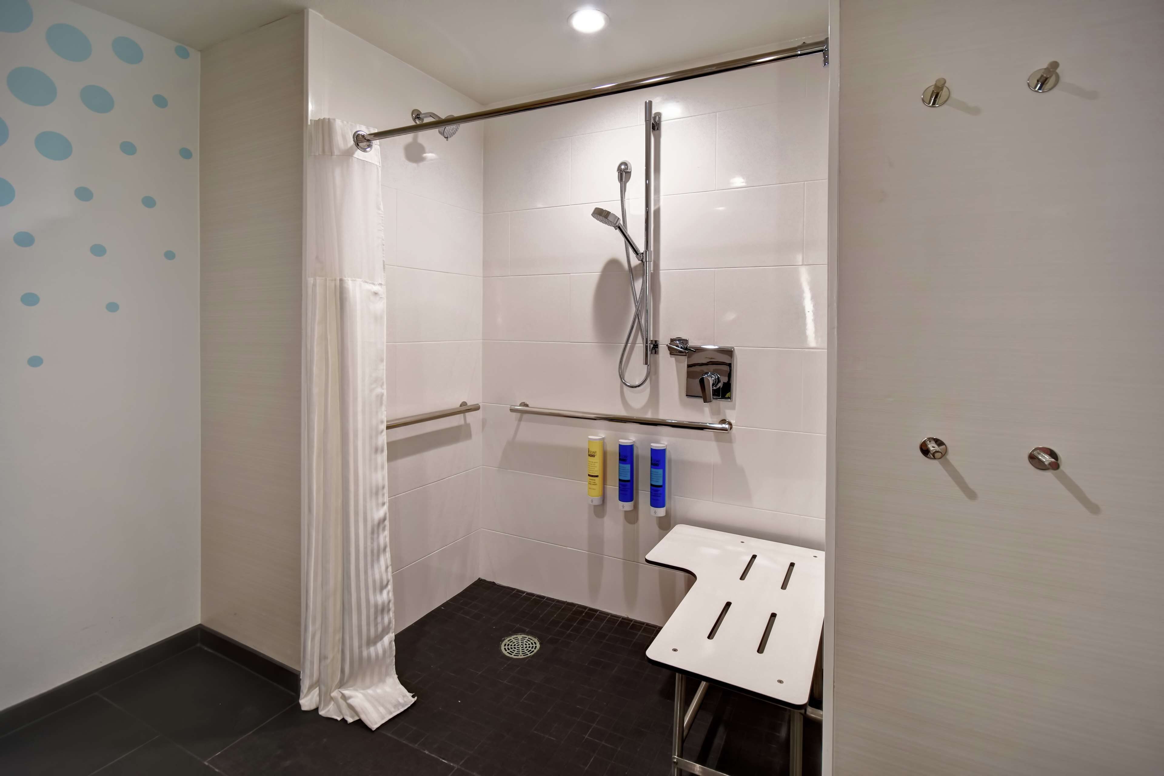A modern bathroom with a shower, a toilet, and a hand sanitizer dispenser.