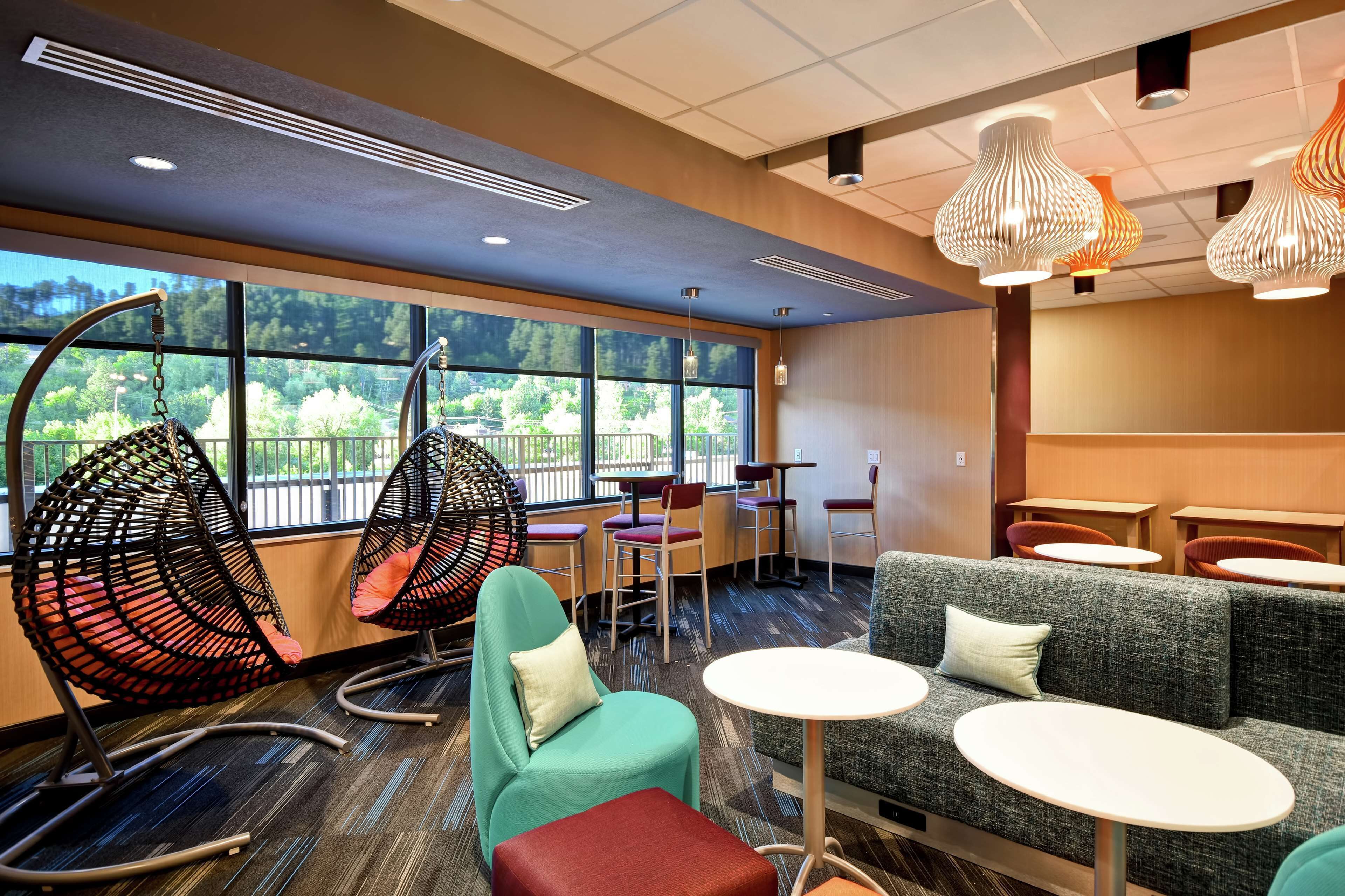 Un área de lounge moderna con diferentes disposiciones de asientos, incluyendo un sofá, sillas y mesas.