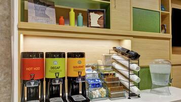 Un espace dédié au café, équipé de trois distributeurs de boissons étiquetés « EAU CHAUDE », « CAFÉ DÉCAFÉINÉ » et « CAFÉ DE QUALITÉ ».