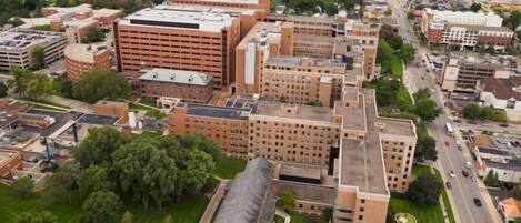 Vista aérea de un campus con varios edificios, incluyendo una gran estructura de ladrillo con techo plano y un edificio más pequeño con cúpula.
