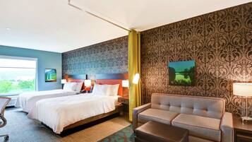 A hotel room with two beds, a sofa, a chair, and a desk.