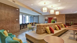 A modern lounge area with a sofa, chairs, and tables. - Home2 Suites by Hilton Rochester Mayo Clinic Area (Rochester)